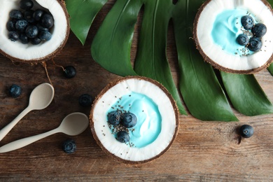 Photo of Coconuts with spirulina smoothie on wooden table, flat lay composition