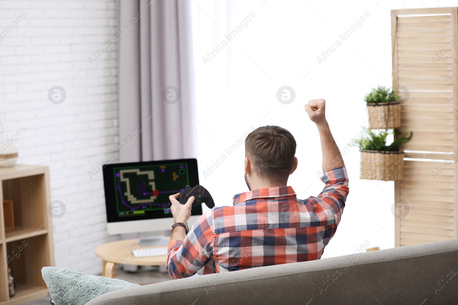 Photo of Young man playing video game at home