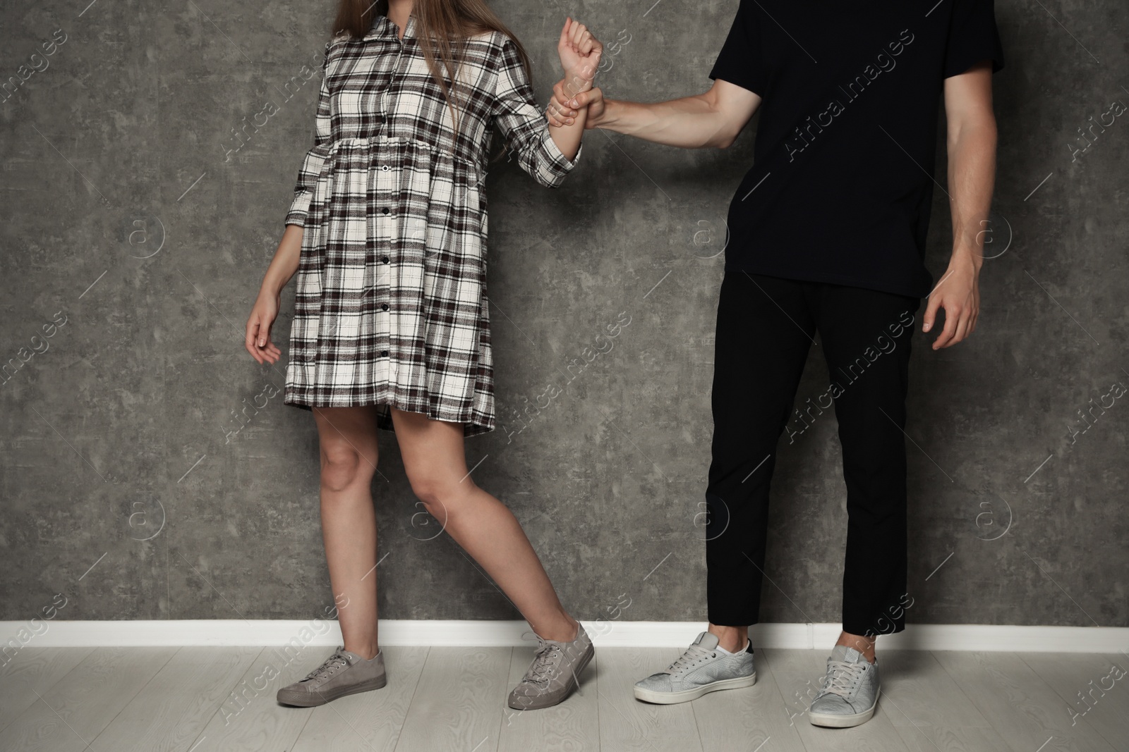 Photo of Man fighting with woman near grey wall, closeup. Stop sexual assault