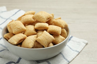 Photo of Bowl of sweet crispy corn pads on white wooden table, closeup. Breakfast cereal