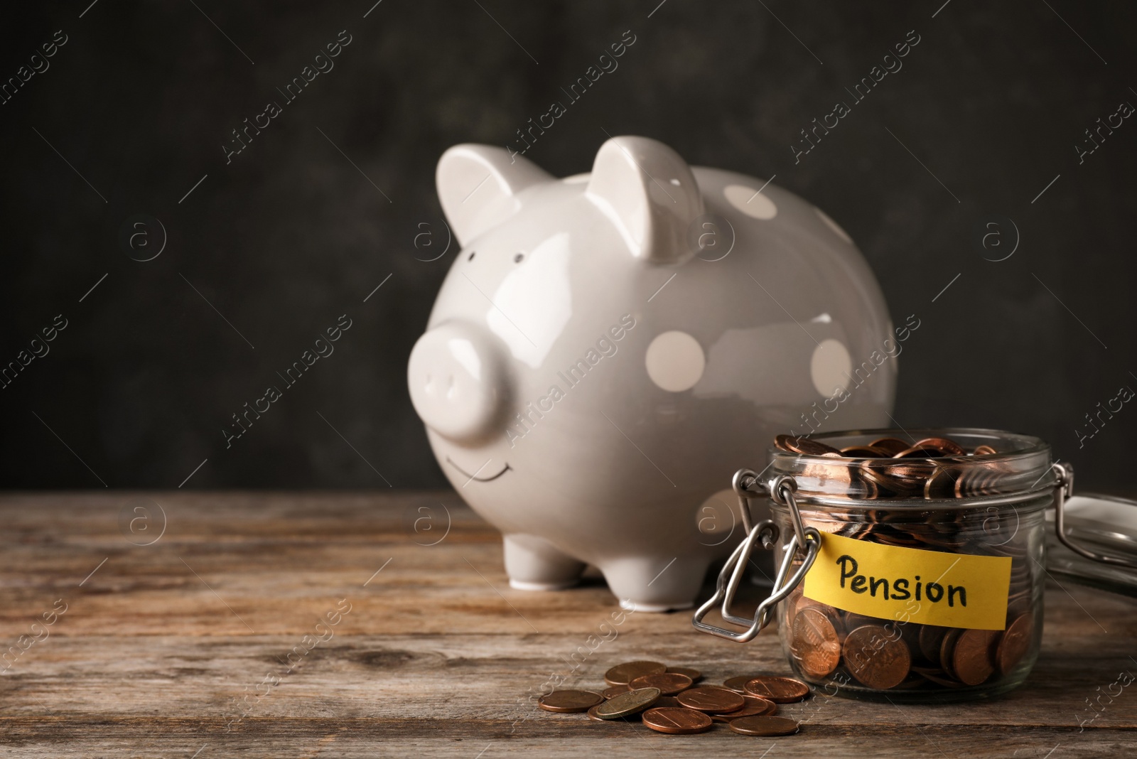 Photo of Piggy bank and jar of coins with word PENSION on table. Space for text