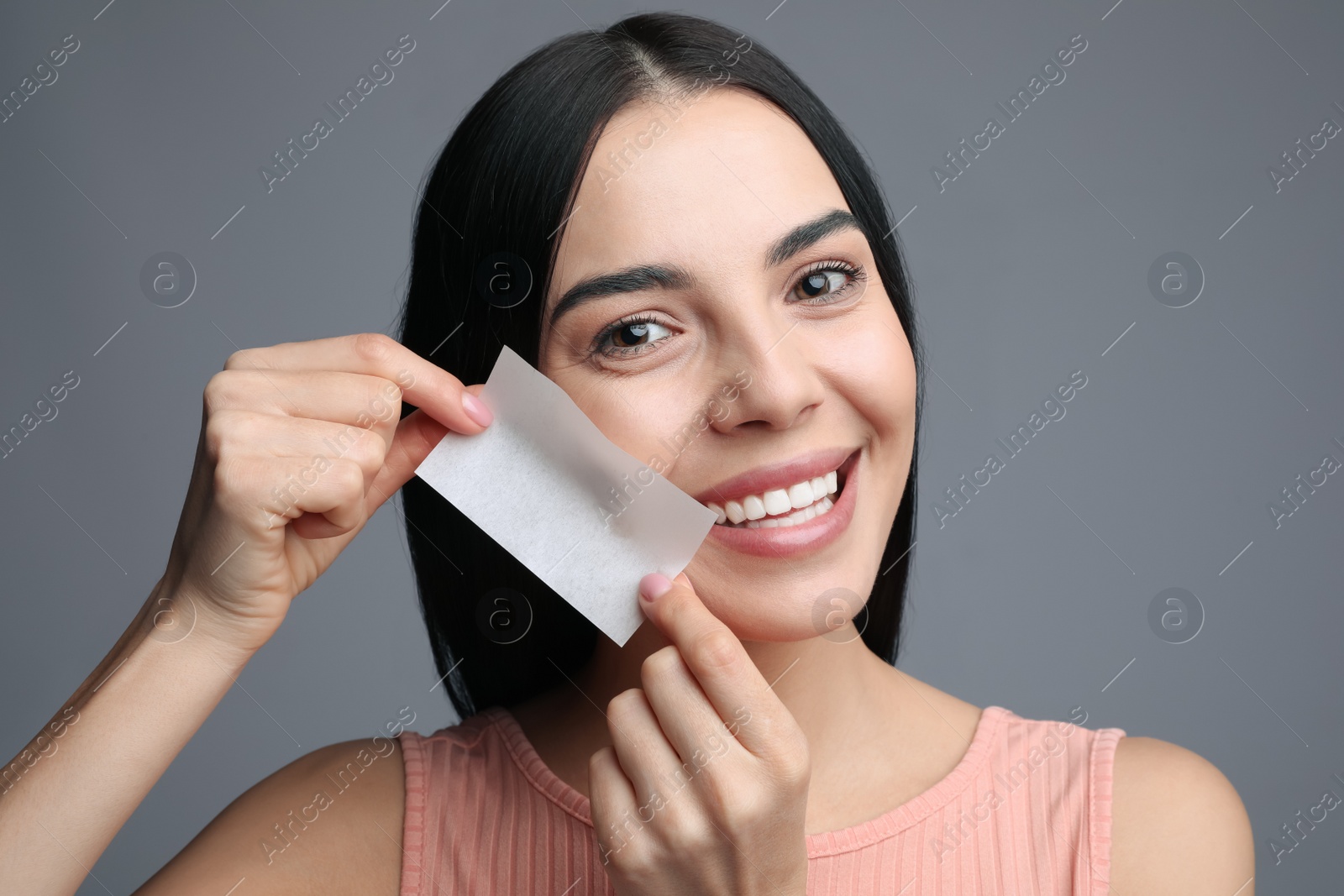 Photo of Beautiful woman using mattifying wipe on grey background