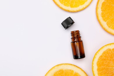 Photo of Bottle of citrus essential oil and fresh orange slices on white background, flat lay. Space for text