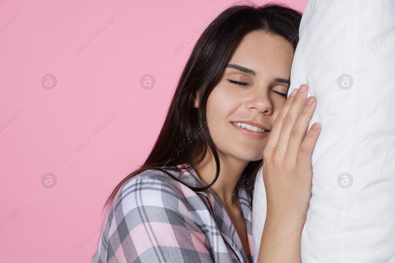 Photo of Sleepy young woman with soft pillow on pink background