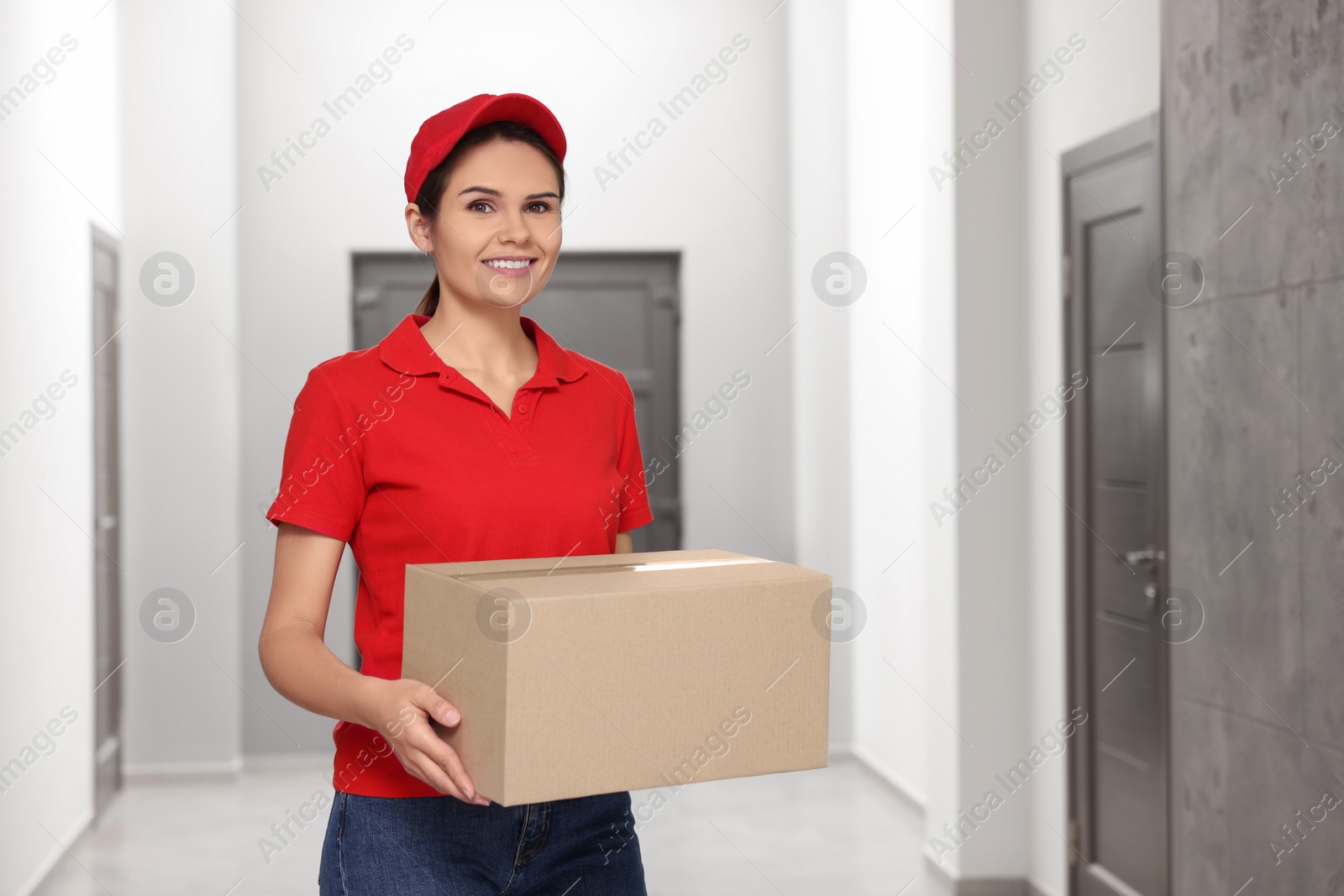 Photo of Smiling courier with cardboard boxes in hallway