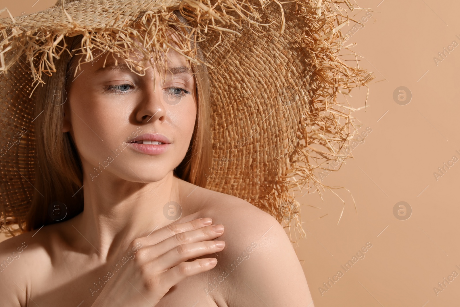 Photo of Beautiful young woman in straw hat on beige background, space for text
