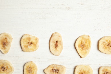Flat lay composition with banana slices on wooden table, space for text. Dried fruit as healthy snack