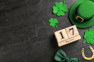 Photo of Leprechaun's hat, block calendar and St. Patrick's day decor on black background, flat lay. Space for text