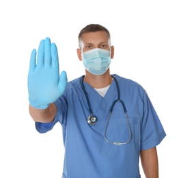 Photo of Doctor in protective mask showing stop gesture on white background. Prevent spreading of coronavirus