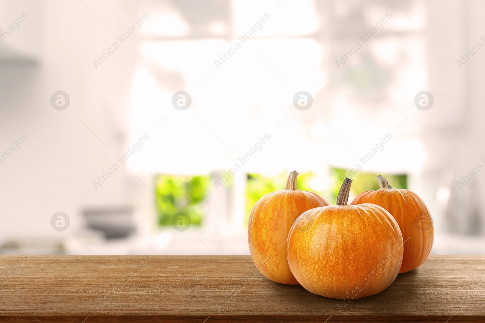 Image of Fresh pumpkins on wooden table in kitchen. Space for text