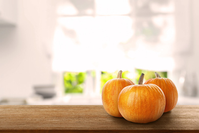 Image of Fresh pumpkins on wooden table in kitchen. Space for text