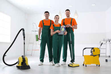 Team of professional janitors with cleaning supplies indoors