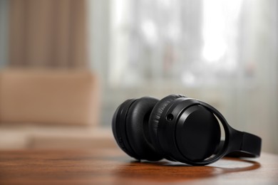 Photo of Modern wireless headphones on wooden table indoors, space for text