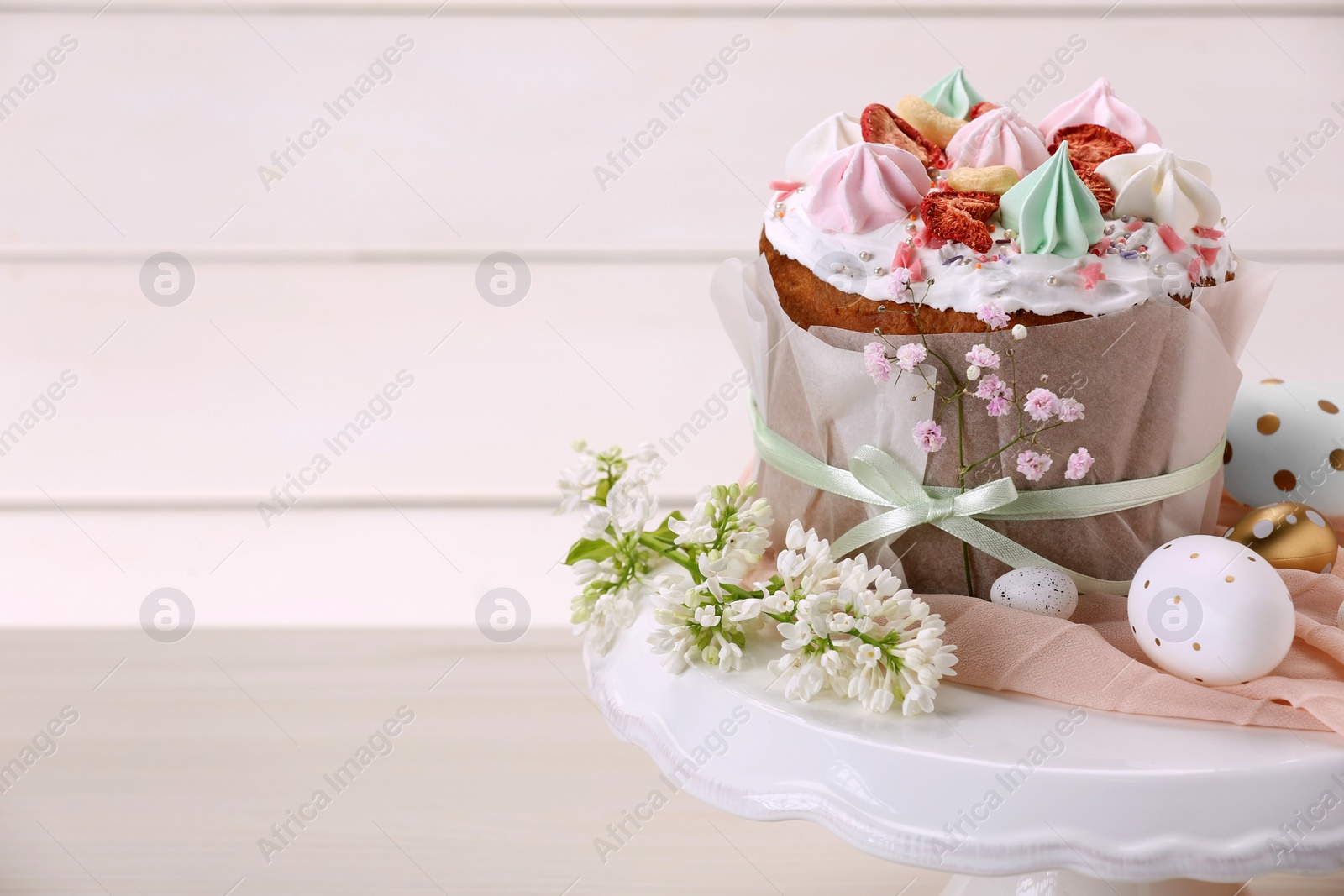 Photo of Traditional Easter cake with meringues and painted eggs on white wooden table, space for text