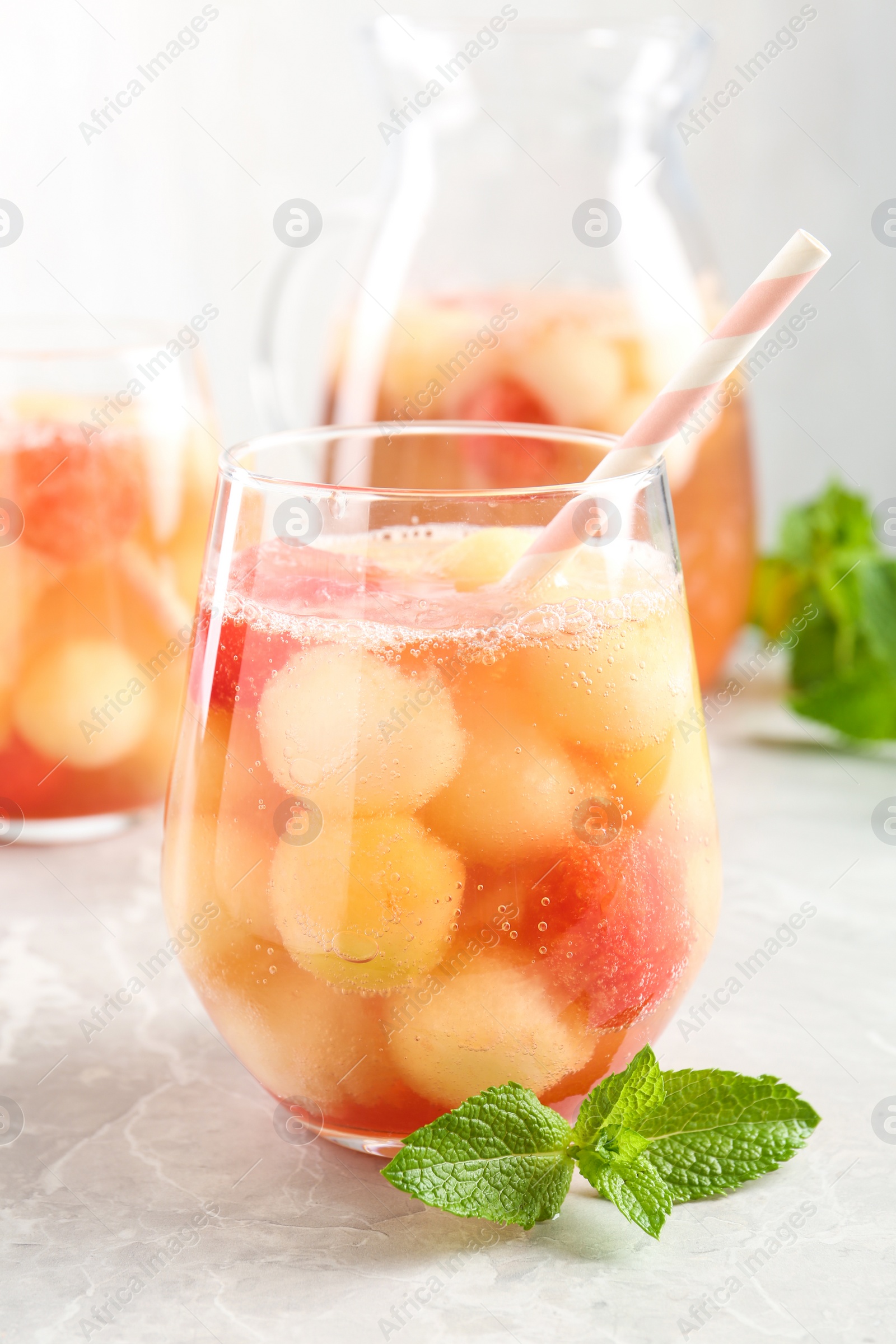 Photo of Glasses of melon and watermelon ball cocktail with mint on light marble table