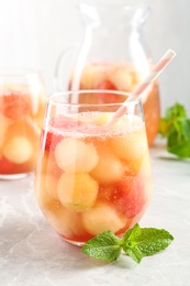 Photo of Glasses of melon and watermelon ball cocktail with mint on light marble table