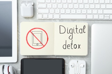 Photo of Flat lay composition of gadgets and notebook with words DIGITAL DETOX on light grey marble background