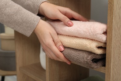 Photo of Woman taking stack of towels in home textiles store, closeup