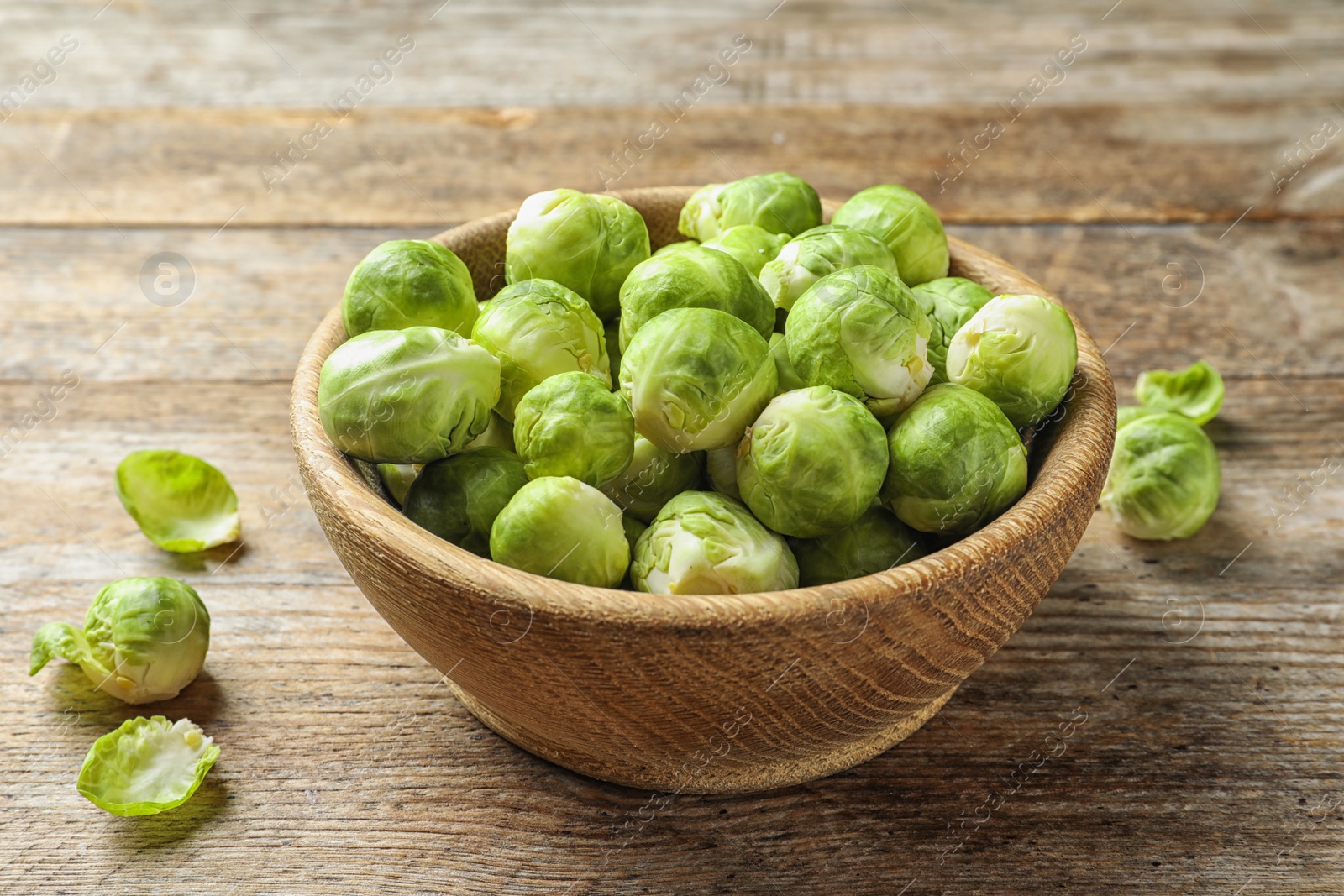 Photo of Bowl of fresh Brussels sprouts on wooden background