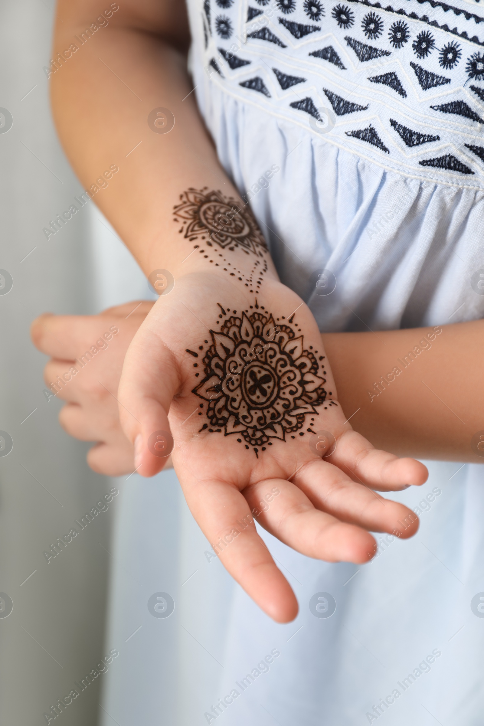 Photo of Little girl with henna tattoo on palm, closeup. Traditional mehndi ornament