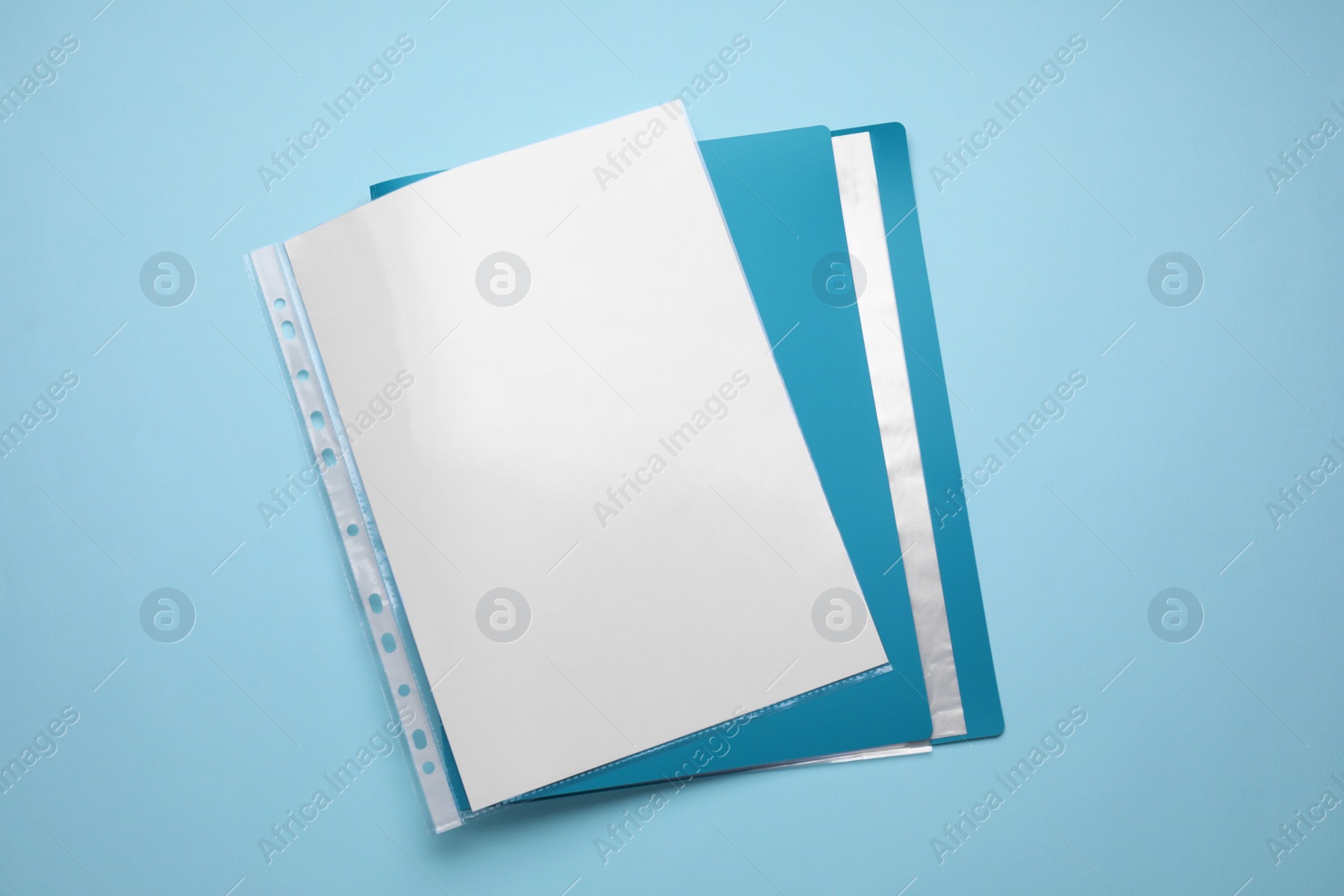 Photo of File folder with punched pockets and paper sheets on turquoise background, top view