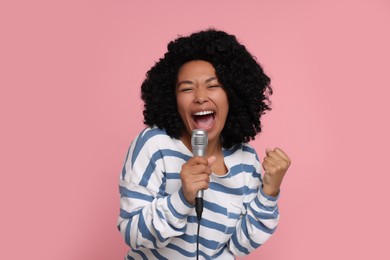 Photo of Beautiful woman with microphone singing on pink background