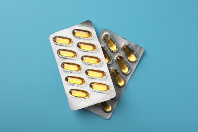 Photo of Dietary supplement capsules in blister packs on light blue background, flat lay