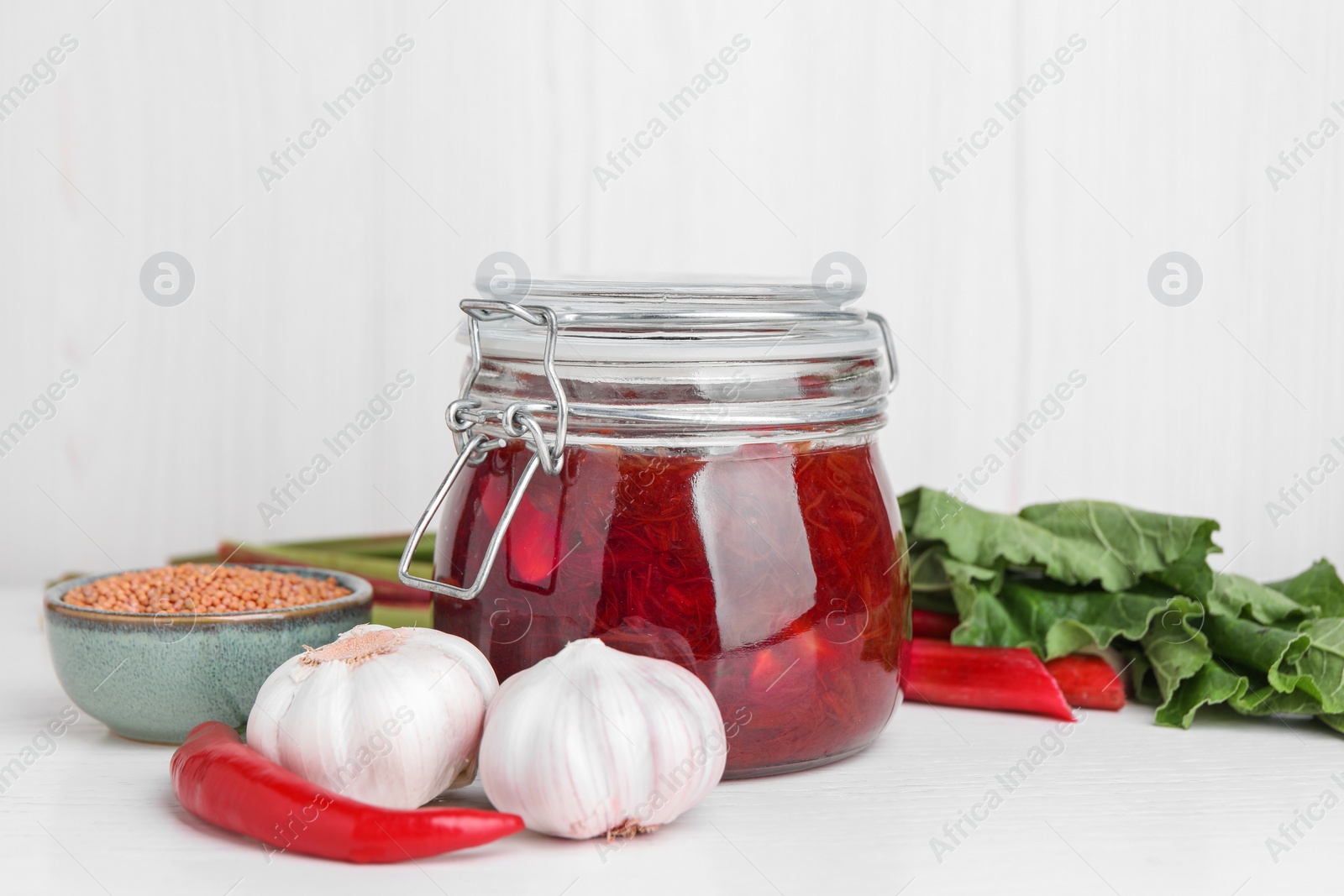 Photo of Tasty rhubarb sauce and ingredients on white table, space for text