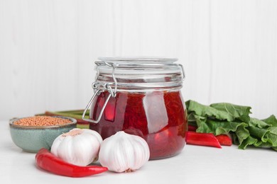 Tasty rhubarb sauce and ingredients on white table, space for text