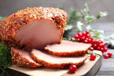 Board with homemade delicious ham on grey wooden table, closeup. Festive dinner