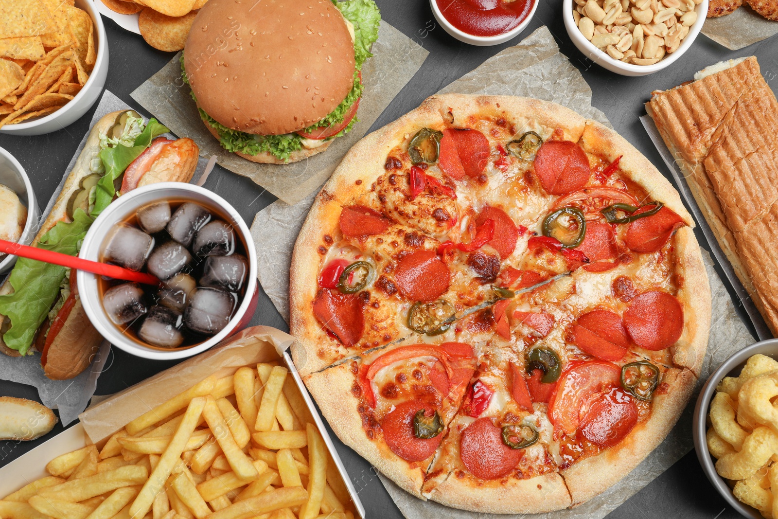 Photo of Pizza, burger and other fast food on black table, flat lay