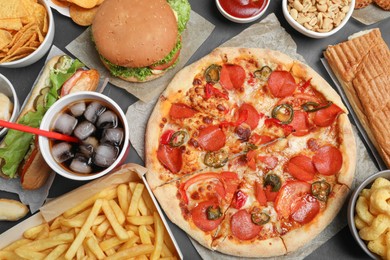 Pizza, burger and other fast food on black table, flat lay