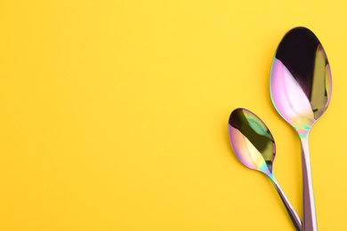 Photo of Clean spoons and space for text on color background, flat lay