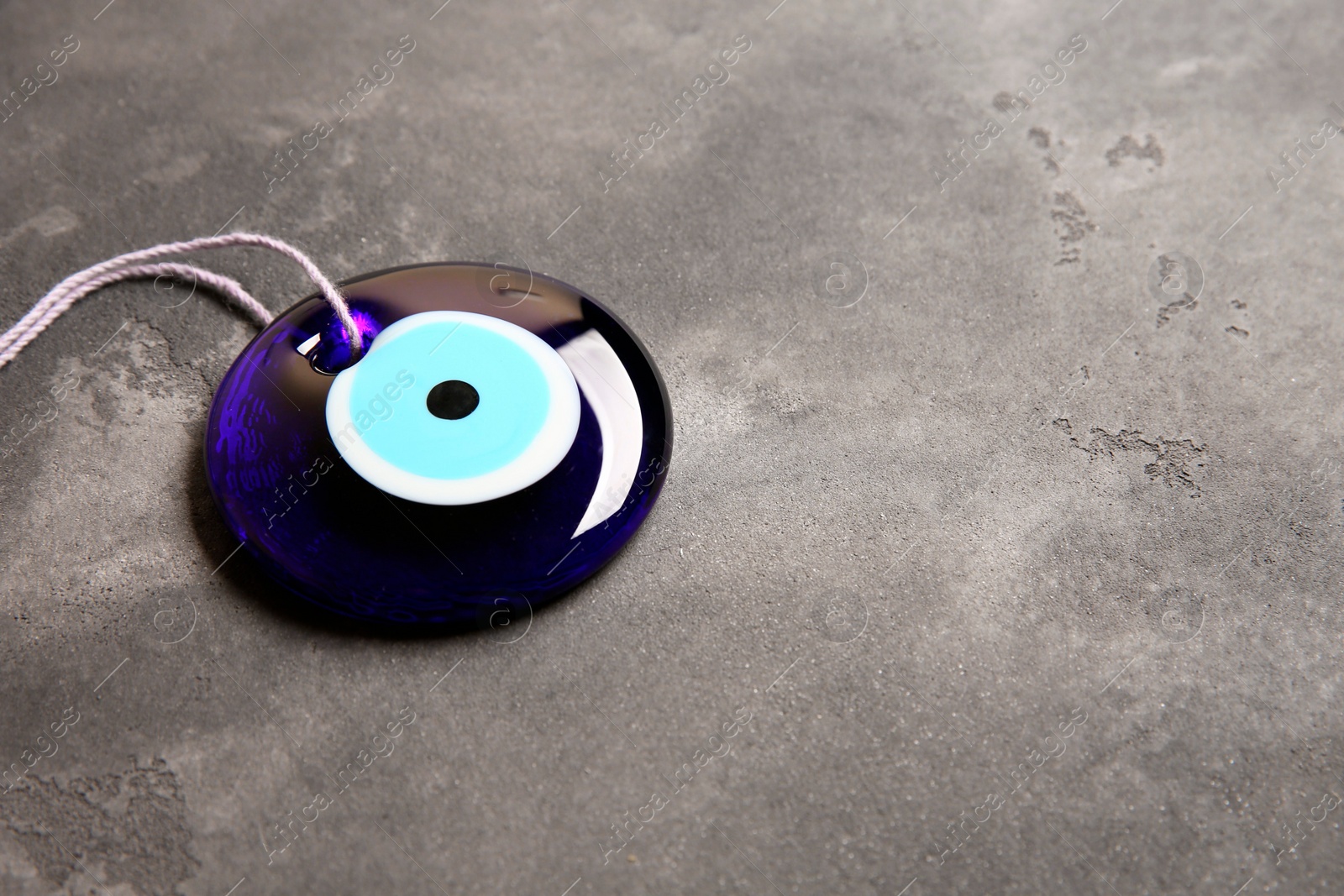 Photo of Traditional evil eye amulet on grey table. Space for text