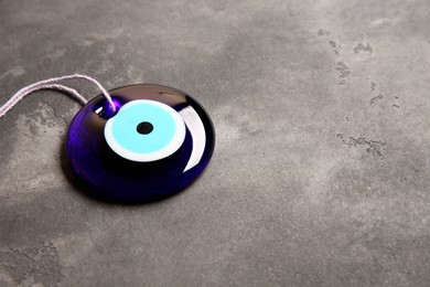 Photo of Traditional evil eye amulet on grey table. Space for text