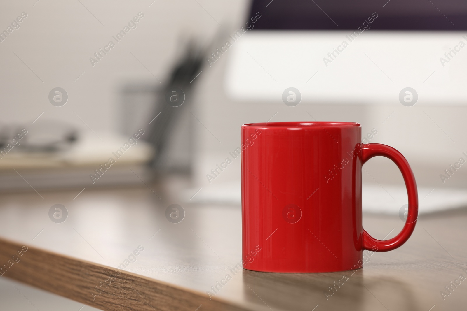 Photo of Red ceramic mug on wooden table at workplace. Space for text