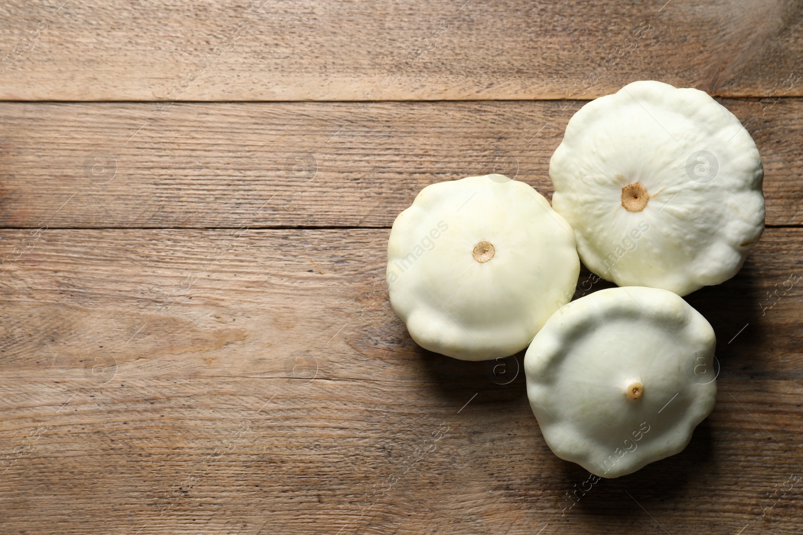 Photo of Fresh ripe white pattypan squashes on wooden table, flat lay. Space for text