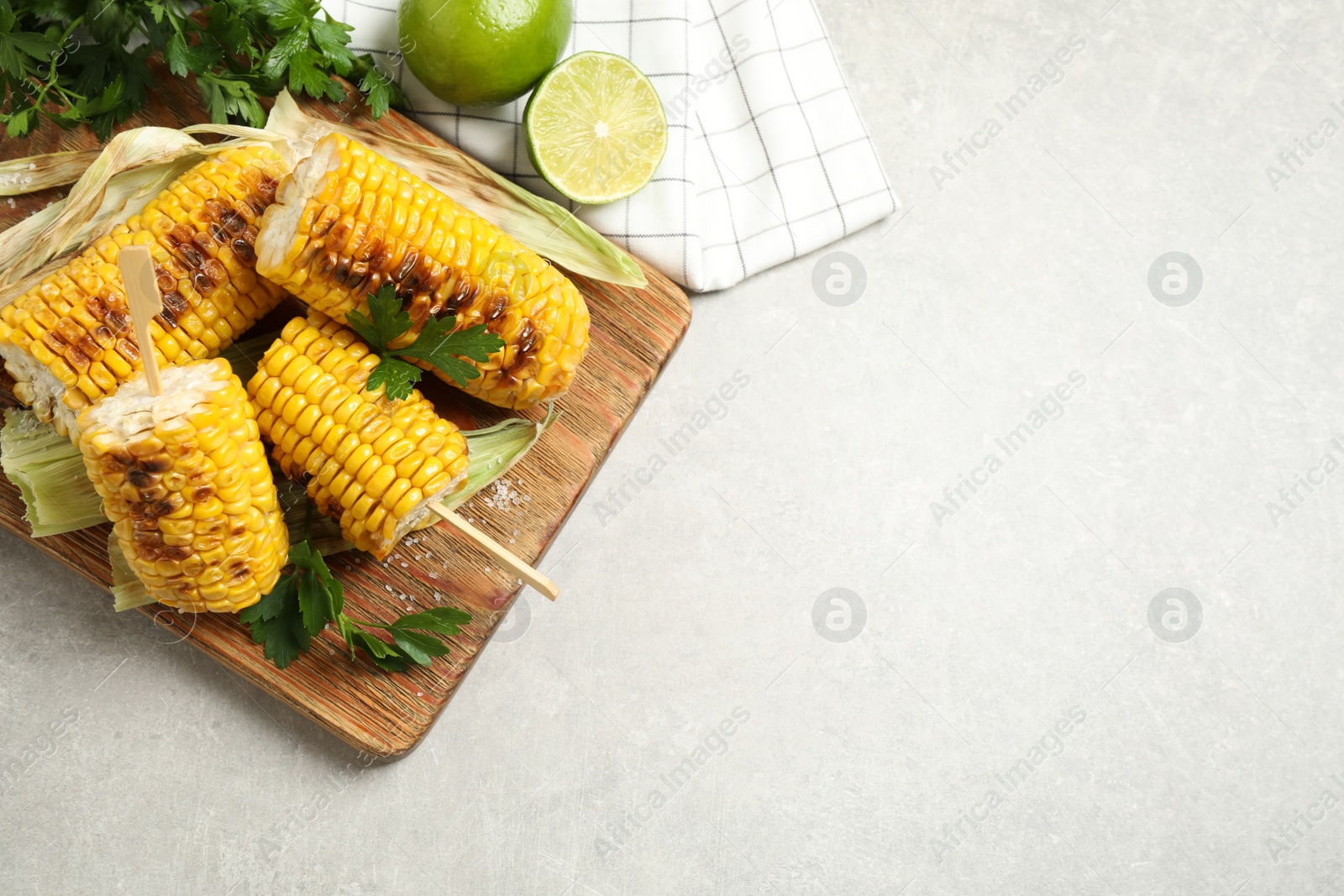 Photo of Tasty grilled corn cobs on light table, flat lay. Space for text