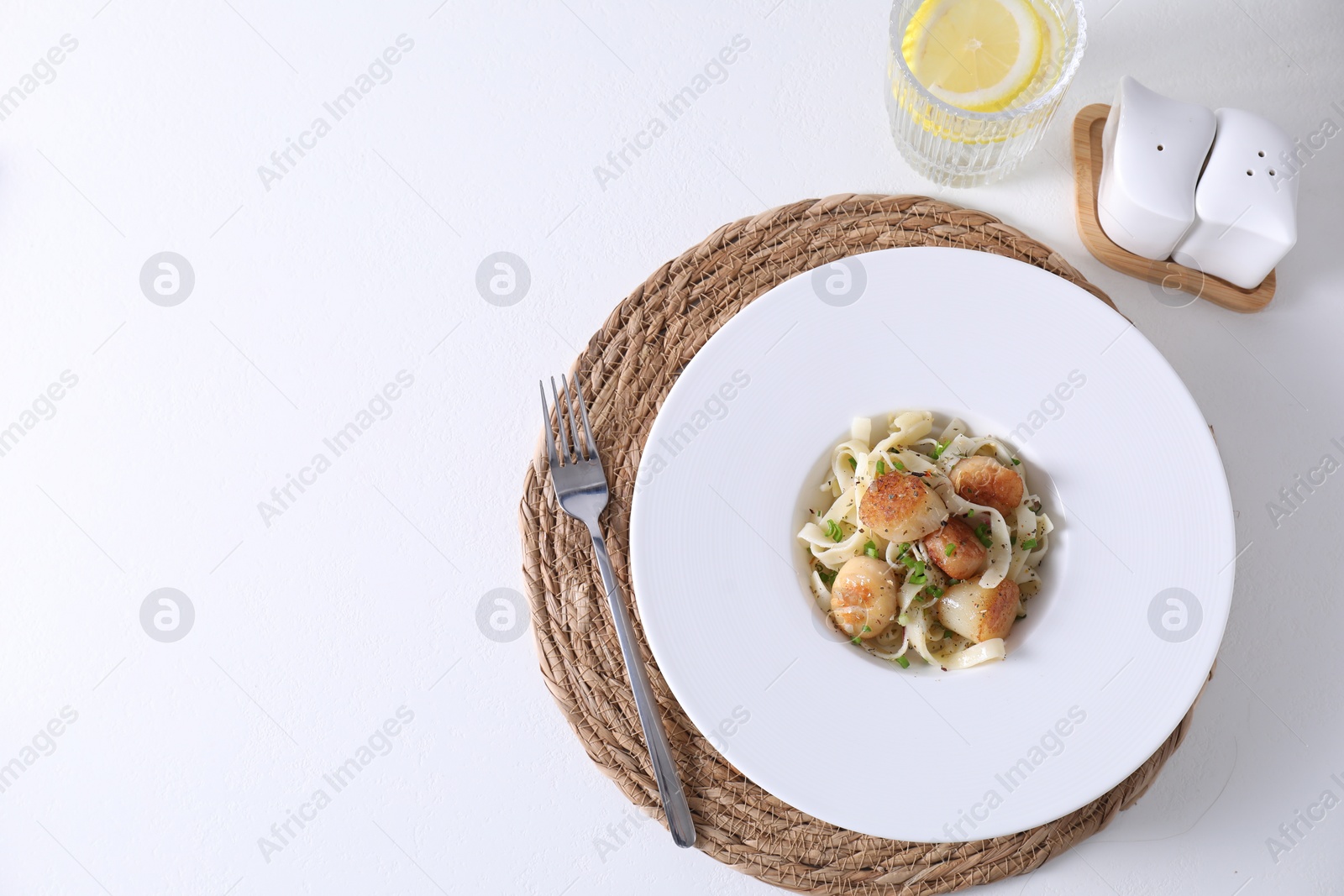 Photo of Delicious scallop pasta with spices in bowl served on white table, flat lay. Space for text