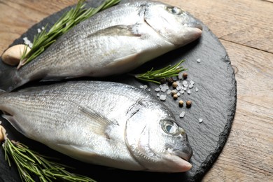 Photo of Raw dorada fish on wooden table, closeup