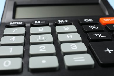 Calculator on light blue background, closeup. Office stationery