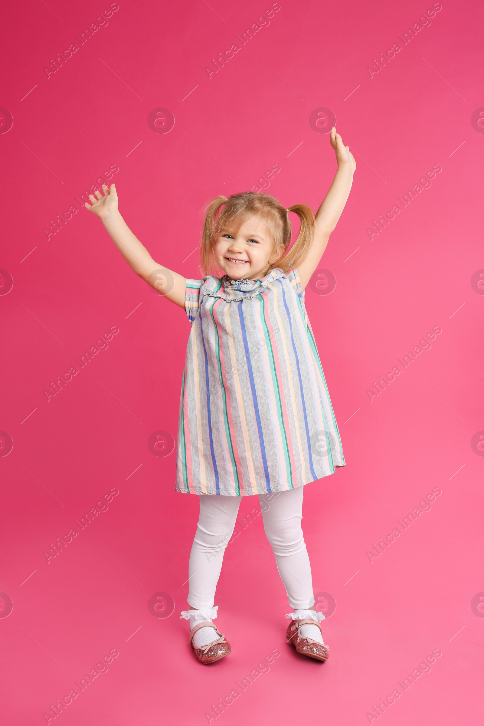 Photo of Portrait of cute little girl on pink background