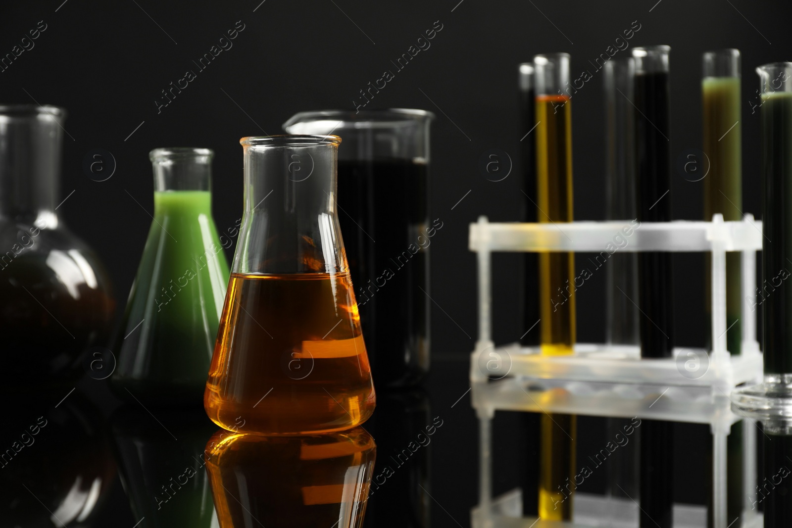 Photo of Laboratory glassware with different types of oil on black background