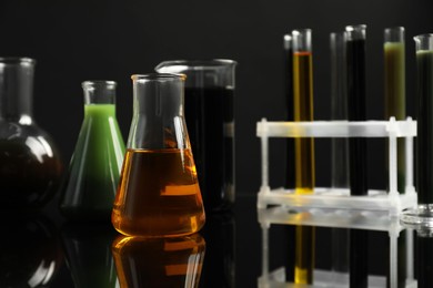 Laboratory glassware with different types of oil on black background