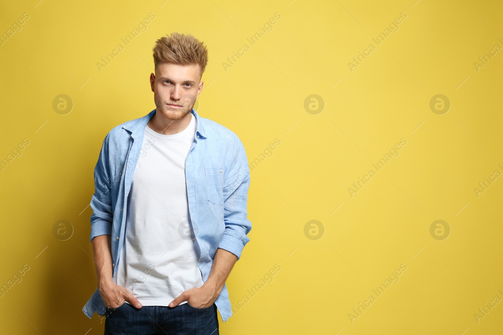 Photo of Young man wearing blank t-shirt on yellow background. Mockup for design