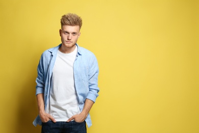 Photo of Young man wearing blank t-shirt on yellow background. Mockup for design