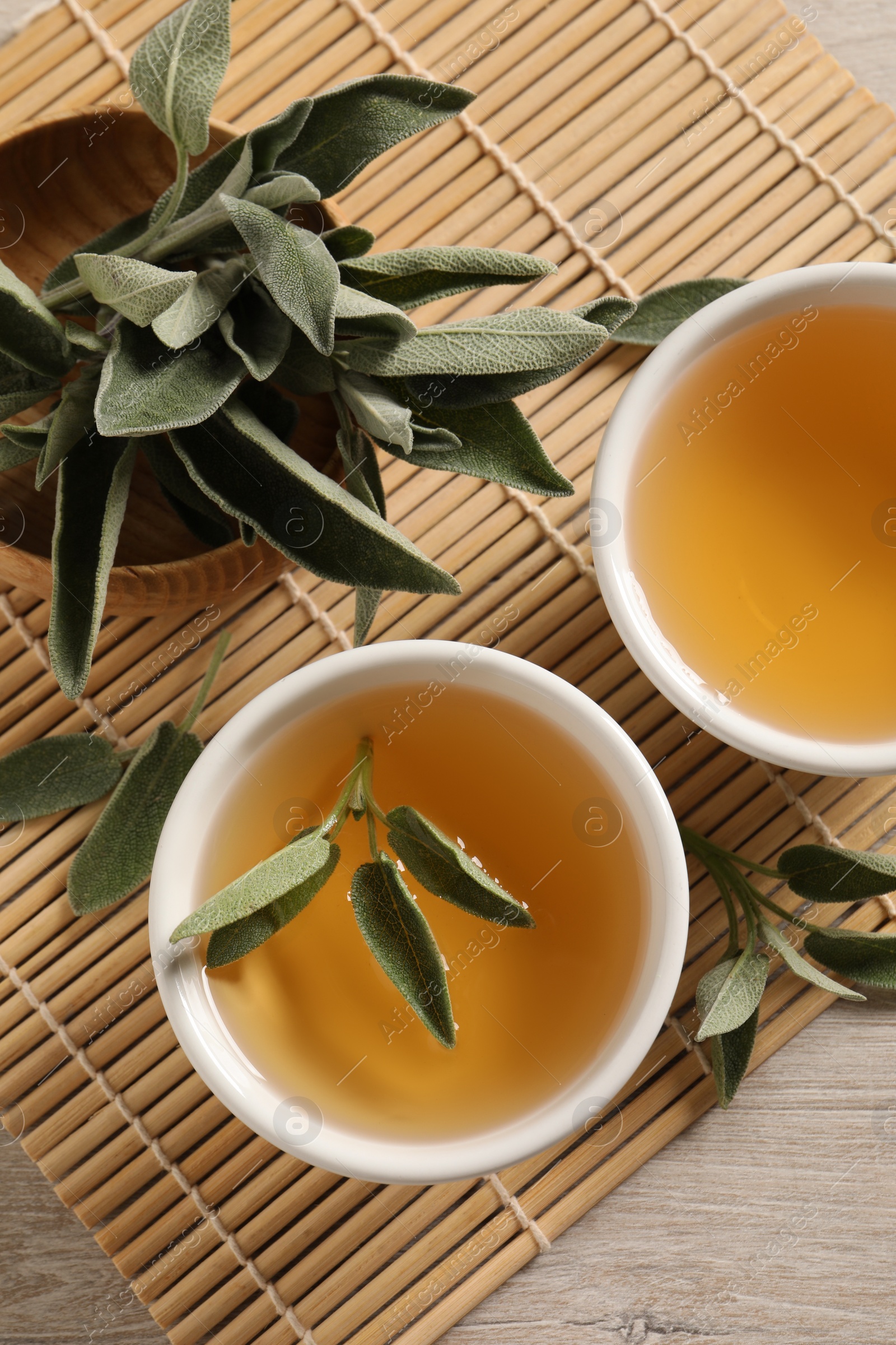 Photo of Aromatic sage tea and fresh leaves on table, flat lay