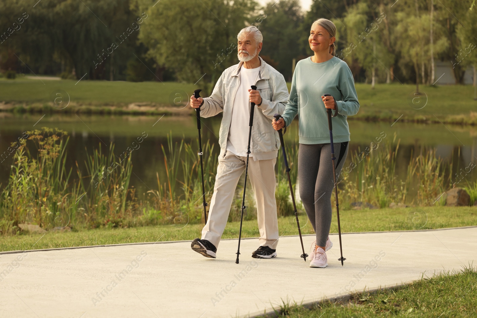 Photo of Senior man and woman performing Nordic walking outdoors, space for text