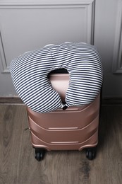 Photo of Striped travel pillow on suitcase near light wall indoors, above view