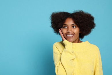Portrait of smiling African American woman on light blue background. Space for text